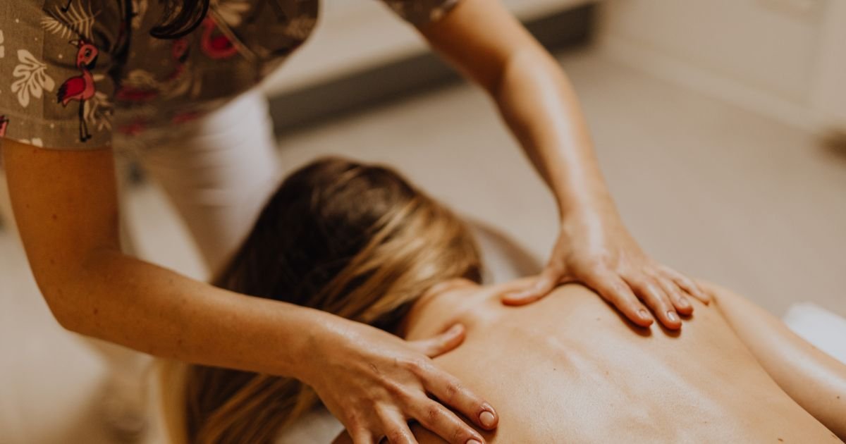 therapist performing swedish massage for a girl lying facing down on a massage table